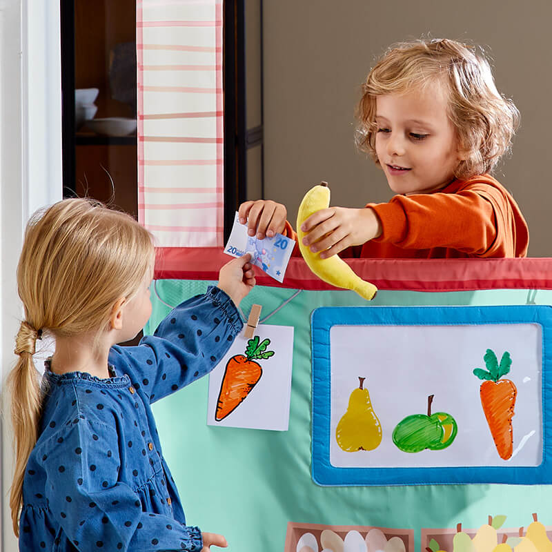 Kid selling play banana to another child through the HABA Doorway Play Store